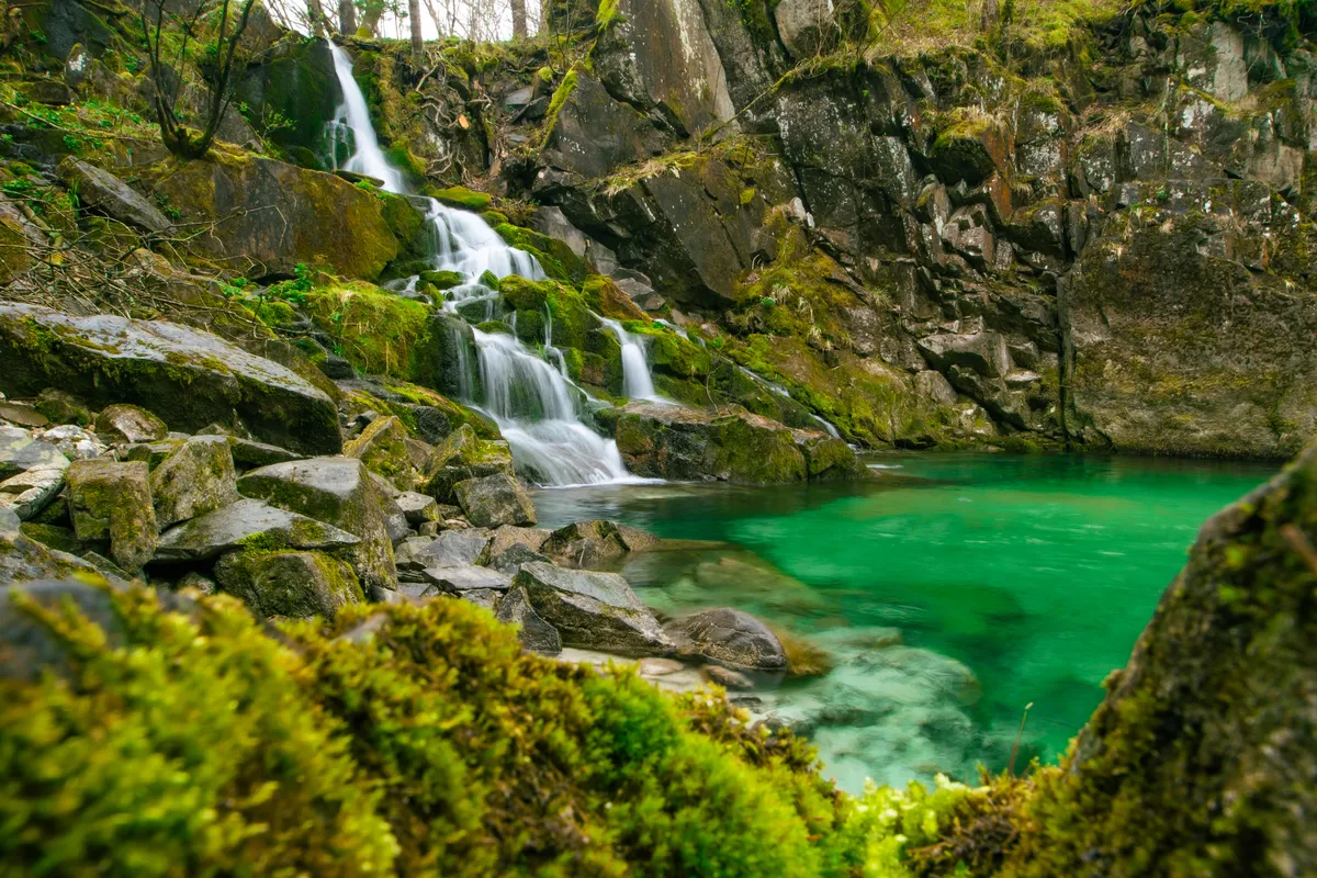Waterfall with emerald pool in the Soča valley